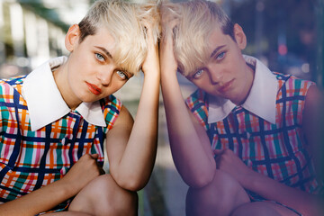 Portrait of female teenager wearing colorful dress mirrored in glass pane
