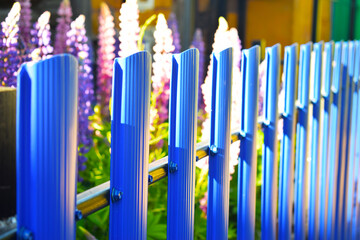 Blue metal picket fence. Fencing near the house and flowers