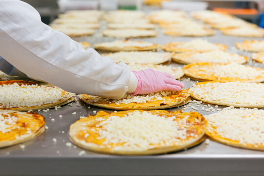 Woman preparing pizzas in pizza company