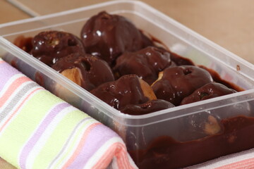 Plastic box with profiterole with chocolate ganache frosting.