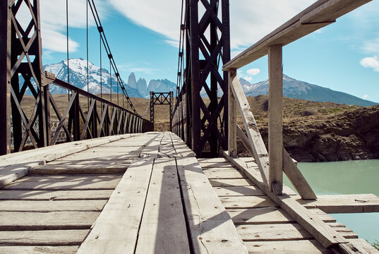 Iron and wood bridge on the water and Torres del Paine mountains at the background, Parque Nacional Torres del Paine, Chile