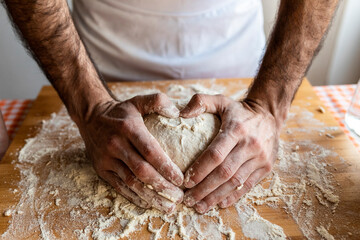 Man's hands shaping heart on dough ball