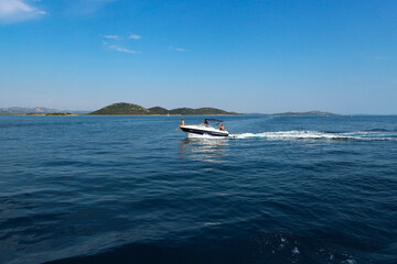 Vrgada/Croatia-July 24th,2017: Speed boat passing by our sailboat in close proximity on the open water in central Dalmatia