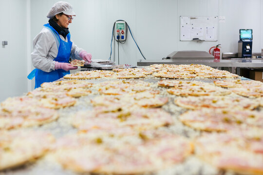 Woman preparing pizzas in pizza company