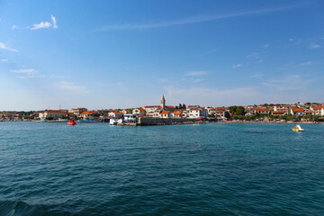 Fototapeta na wymiar Town of Pakostane with its family houses and church tower on the shore, photographed from the boat