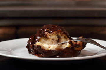 Profiterole with chocolate ganache frosting.  Choux pastry ball with custard filling and chocolate sauce icing.