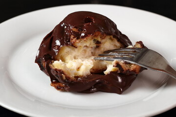 Profiterole with chocolate ganache frosting.  Choux pastry ball with custard filling and chocolate sauce icing.
