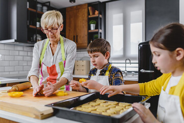 Grandmother baking cookies with her grandchildren at home. Baking cookies. Happy grandmother with...