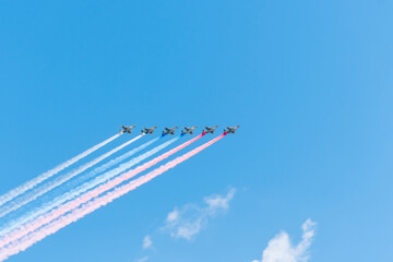 Group of airplanes makes Russian flag in the sky with colorful smoke, red, blue and white. 