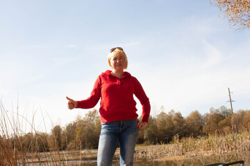 woman in red with finger up on the bank of the lake