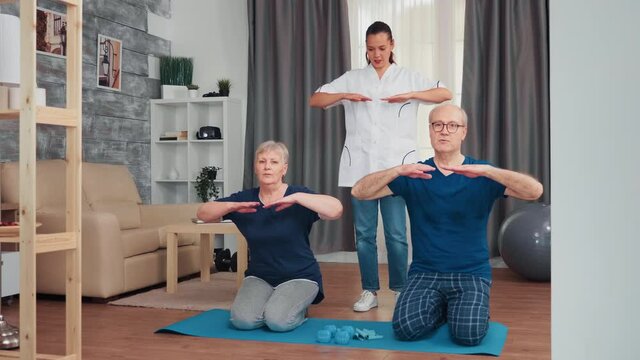 Senior couple doing physical therapy with doctor at home. Home assistance, physiotherapy, healthy lifestyle for old person, training and healthy lifestyle
