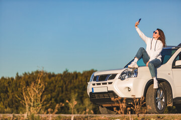 woman near white suv car enjoying sunset