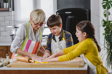 Grandmother baking cookies with her grandchildren at home. Baking cookies. Happy grandmother with...