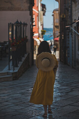 Fototapeta na wymiar young pretty woman in yellow dress walking by small porec city streets sea on background