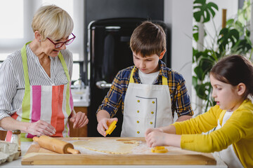 Grandmother baking cookies with her grandchildren at home. Baking cookies. Happy grandmother with...