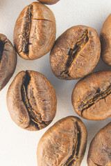 Brown coffee grains on a white paper background. Fragrant coffee grains close-up.