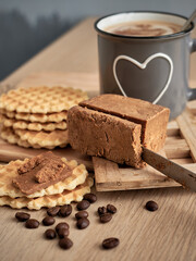 Viennese waffles with Norwegian brunost cheese with a cup of coffee in the background. Breakfast with Traditional Scandinavian brown cheese