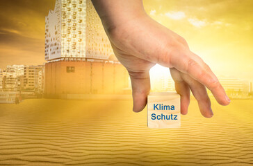 konzept bild eine hand hält einen würfel mit der aufschrift Klima Schutz im Hintergrund der Hamburger Hafen