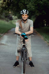 Portrait of man in a yellow sunglasses and helmet standing with bicycle on road and looking into camera. High quality