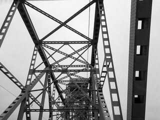 Metal construction of the railway bridge with the rising middle part for the passage of ships. View from below from the car window. Architecture, design elements