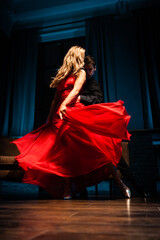 Dance and love concept. Young couple in elegant evening dresses posing in the room filled with...