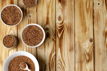 Bowl of raw uncooked buckwheat on wooden table