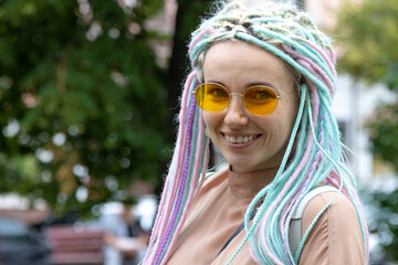 Portrait of a young fun woman with dreadlocks hairstyle in yellow fashionable glasses.