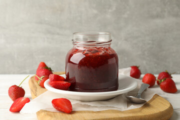 Composition with strawberry jam on wooden table against gray background