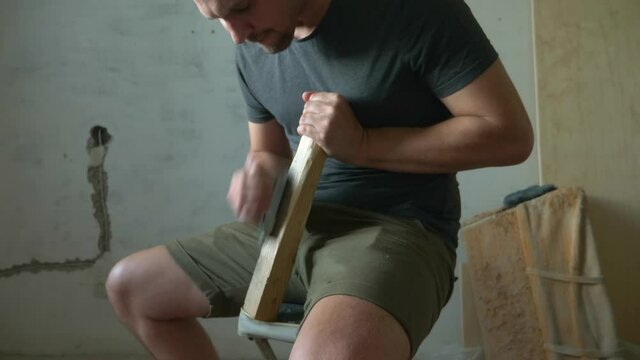 bald man planes a planer wooden bar sitting indoors