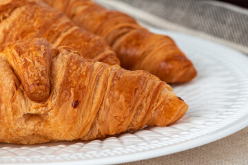 Fresh baked croissant on wooden table close up
