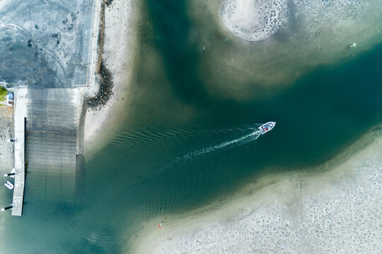 A small powerboat motors away from a boat ramp.