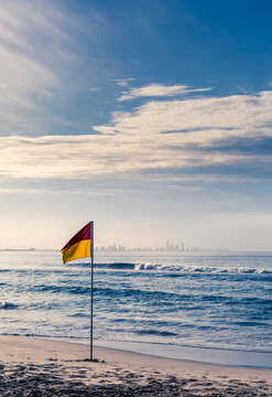 Surf Life Saving flag on beach with city in background