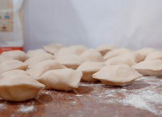 Sculpt dumplings. Dumplings with minced meat sculpts cook in the kitchen. Dumplings on the table sprinkled with flour.