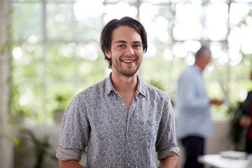 Young professional man standing in an open plan office