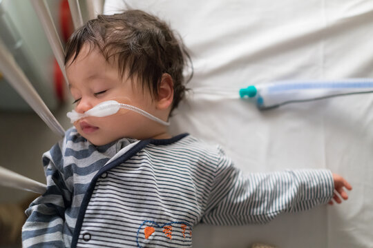 Sick mixed race year old boy asleep being treated with oxygen therapy in Children's Hospital ward