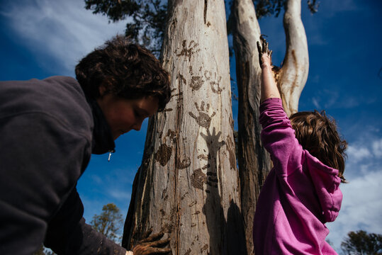 Low angle view of girls making hand prints on gum tree