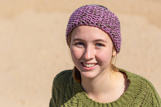 Smiling young woman looking at camera in sunshine head and shoulders