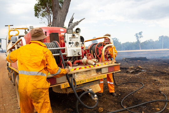 volunteer firefighters winding hoses onto firetruck on a farm