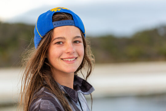 Girl with tousled brown hair wearing baseball cap backwards