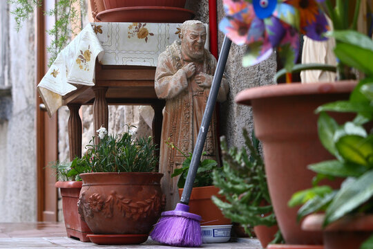 Image from the ground of the door of an Italian village house, statue of San Pio in the midst of household objects