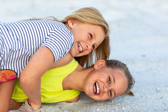 young siblings wrestling and laughing on the ground