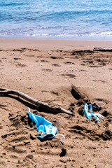 Medical face masks used and thrown on the floor of an empty beach. Covid coronavirus contamination in the sea.