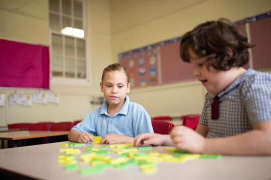 Two girl school students collaborating with coloured word tiles