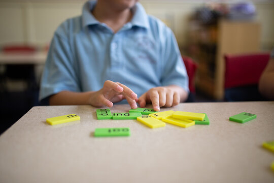 Closeup of primary school student's hands working with green and yellow word tiles