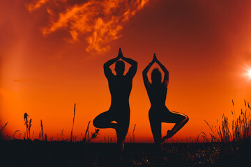 silhouette of a couple of people in a yoga pose at sunset