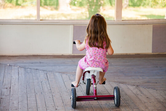 Girl riding tricycle on veranda at homestead