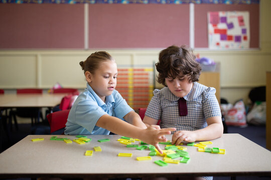 Two primary school girl students collaborating with coloured word tiles