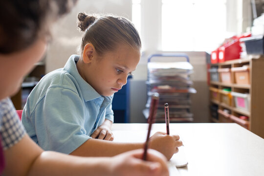 Side view of an indigenous primary school student writing in a classroom