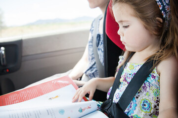 Young girl reading a book in the car
