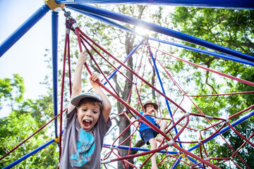 Young boy climbing spiderweb playground equipment at park
